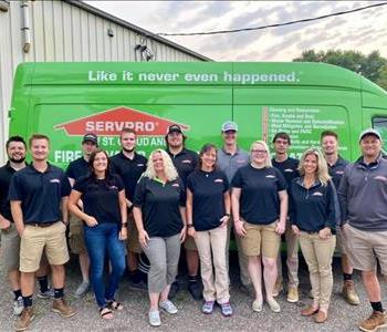 Male and female employees in front of green SERVPRO vehicle.
